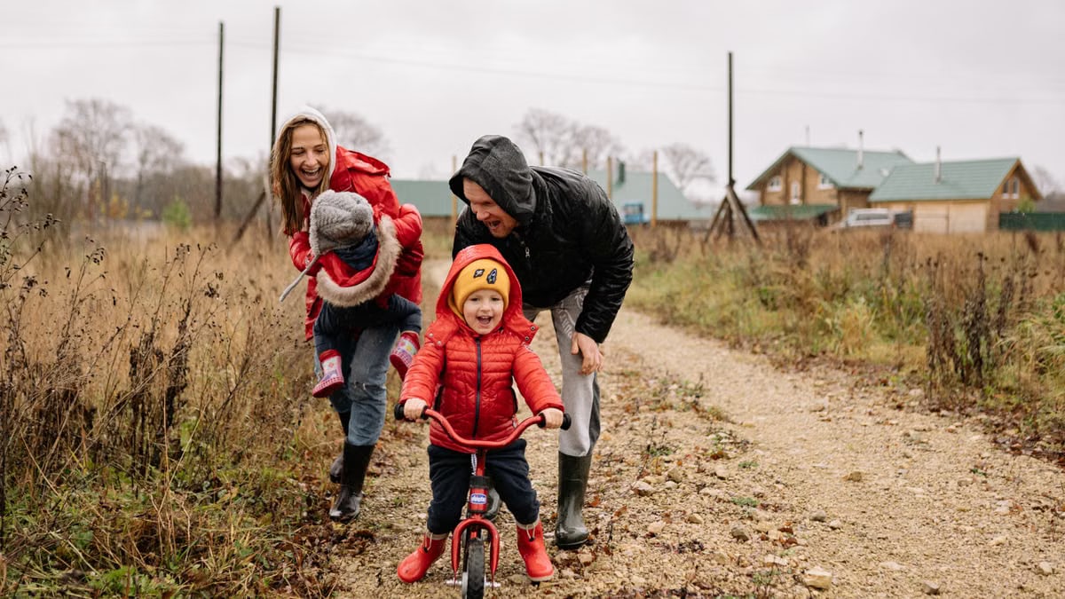 Happy family enjoying a rainy day outside with a bike ride and playful togetherness.